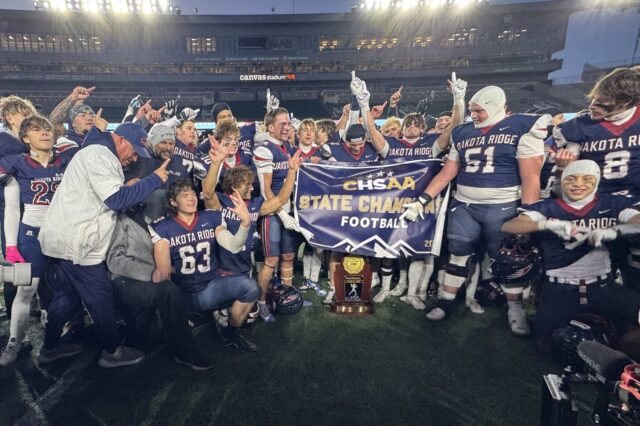 Dakota Ridge players gather around the 4A championship trophy